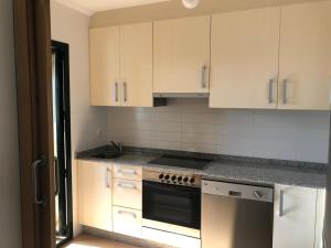 eine Küche mit weißen Schränken und einem Herd mit Backofen in der Unterkunft Apartamento para 6 personas con piscina y paddle in Foz