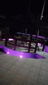 a wooden picnic table with purple lights on the ground at Chácara Felicidade Um pedacinho do Céu in Mairiporã