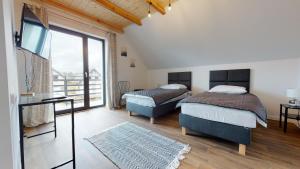two beds in a room with a large window at Przystanek Orle in Gorczyca