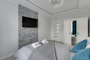 グダニスクにあるComfort Apartments Old Town Groblaのレンガの壁にテレビとベッドが備わるベッドルーム1室が備わります。