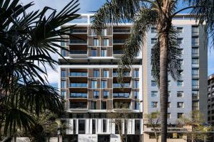 瓦伦西亚Apartamentos Core Suites Valencia的一栋高大的白色建筑，前面有棕榈树