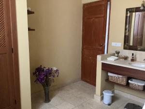ein Badezimmer mit einem Waschbecken und einer Vase aus Blumen in der Unterkunft Cortijo de la Fuente in Albuñol