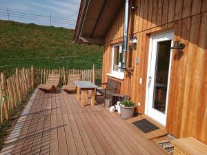 una terraza de madera con sillas y un banco en una casa en s'heimatgfühl, en Schwarzenberg