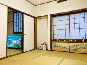 a living room with large windows and a flat screen tv at Green House 101 in Tokyo