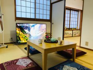 a living room with a table and a large screen tv at Green House 101 in Tokyo