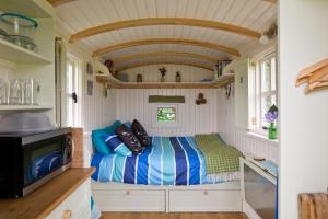 a small room with a bed in a tiny house at Mill Farm Shepherds Hut in Great Driffield