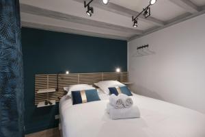 a bedroom with a large white bed with towels on it at DIFY Quatre Chapeaux - Centre ville in Lyon
