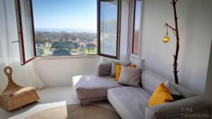 a living room with a couch and a large window at São João da Caparica Beach Apartment in Costa da Caparica