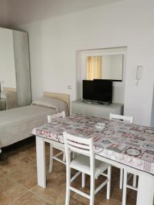 mesa de comedor blanca con sillas y TV en Loft San Mauro, en Viagrande