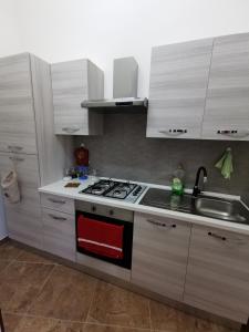 cocina con armarios blancos, fogones y fregadero en Loft San Mauro, en Viagrande