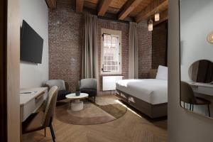 a bedroom with a bed and a desk and a tv at Hotel Arsenaal Delft in Delft