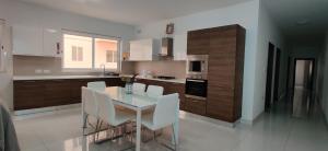 una cucina con tavolo in vetro e sedie bianche di Lorenza Letting Maisonette a Marsaxlokk
