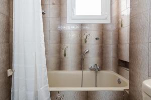 a bathroom with a tub with a window and a shower curtain at Nice 2bedroom apartment in Pagkrati in Athens +16 photos