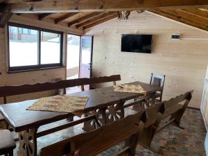 a dining room with wooden tables and chairs and a tv at Вили Елеганс Сърница in Sarnitsa
