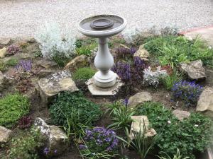 un jardín con un baño de aves y flores en The New Inn Motel, en York