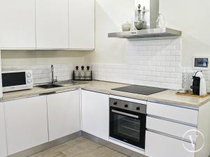 una cucina con mobili bianchi e un forno a piano cottura di Elegante e panoramico Appartamento a Montecatini Terme