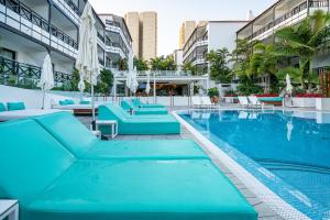 a large swimming pool with blue chairs and umbrellas at Vanilla Garden Boutique Hotel - Adults Only in Playa de las Americas