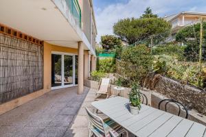 eine Terrasse mit einem Tisch und Stühlen sowie ein Gebäude in der Unterkunft Le Cap in Cassis