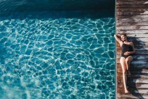 a woman in a swimsuit sitting in a swimming pool at Hotel Rudolf in Brunico