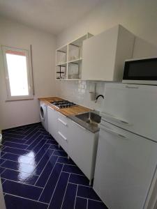 a kitchen with white cabinets and a blue tile floor at Casa Vacanze Playa 54 in Castellammare del Golfo