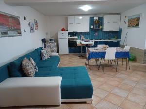 een woonkamer met een blauwe bank en een keuken bij CASA ORCHIDEA in Carlentini