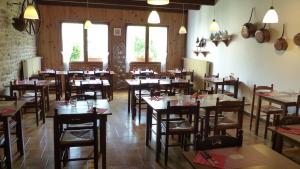 un restaurante con mesas y sillas de madera y ventanas en Tente Cabane du Camping Hautoreille en Bannes