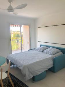 Un dormitorio con una cama azul y una ventana. en Appartement la Frégate avec terrasse à 100m de la plage, en Saint-Cyr-sur-Mer