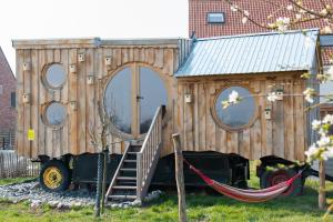 una pequeña casa de madera con una hamaca frente a ella en Origineel logeren bij Dagbreek, en Westerlo