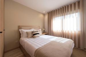 a bedroom with a large bed and a window at Oliva Welcoming Apartments in Proença-a-Nova