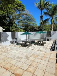 un patio con mesas de picnic y sombrillas en Guest house on Gillian Unit 1, en Ballito