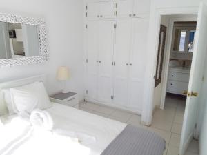 プラヤ・デル・クーラにあるMonseñor Ocean View Apartmentの白いベッドルーム(白いベッド1台、鏡付)