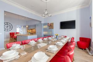 a long wooden table with red chairs and a kitchen at Carlton House Portpatrick in Portpatrick