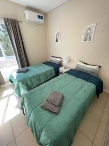 sypialnia z 2 łóżkami i zieloną pościelą w obiekcie Moderno Departamento con cochera w mieście Mendoza