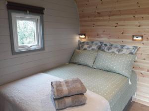 Cama en habitación pequeña con ventana en Rowan - Luxury Pod at Trewithen Farm Glamping en Launceston