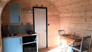 a kitchen with a table and a door in a room at Hornbeam Luxury Eco Pod at Trewithen Farm Glamping in Launceston