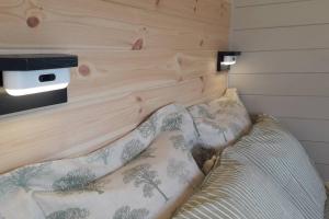 a bed with a wooden headboard with pillows on it at Hornbeam Luxury Eco Pod at Trewithen Farm Glamping in Launceston