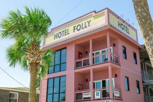 a pink hotel with a palm tree in front of it at Hotel Folly with Marsh and Sunset Views in Folly Beach