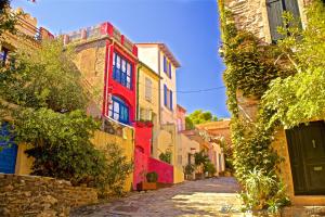 une ruelle dans une vieille ville avec des bâtiments colorés dans l'établissement The Originals City, Hôtel Les Dômes, Perpignan Sud Saleilles, à Perpignan