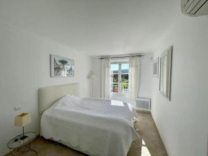a white bedroom with a bed and a window at Charmantes Haus im Golf Club Saint Tropez in Saint-Tropez