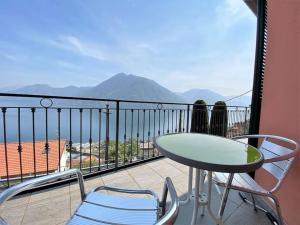 a table and chairs on a balcony with a view at San Sisinio Apartment Argegno in Argegno