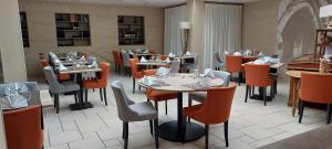 un comedor con mesas y sillas en un restaurante en Logis hôtel le relais de l'abbaye, en Saint-Évroult-Notre-Dame-du-Bois