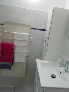 ein weißes Bad mit einem Waschbecken und einem roten Handtuch in der Unterkunft ANCRE BLEU in Hillion