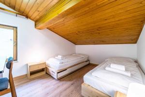 2 łóżka w pokoju z drewnianym sufitem w obiekcie Casa Mirabella w mieście Sottoguda