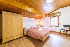 1 dormitorio con cama y techo de madera en Casa Mirabella, en Sottoguda