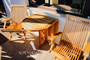 Alpenhoamat Apartments في غارميش - بارتنكيرشين: طاولة خشبية و كرسيين للجلوس بجانب طاولة