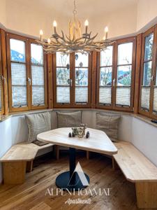 Habitación con mesa, bancos y ventanas. en Alpenhoamat Apartments en Garmisch-Partenkirchen