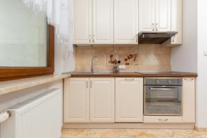 a kitchen with white cabinets and a sink at Apartament Na Woli Sowińskiego by Renters in Warsaw