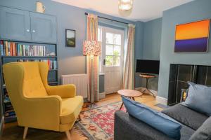 sala de estar con silla amarilla y sofá en Cliffe Cottage, en Lewes