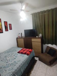 a bedroom with a bed and a dresser with a television at Serra Negra - Melhor localização da cidade in Serra Negra
