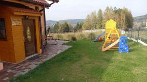 einen Hof mit einem Spielplatz und einem gelben Haus in der Unterkunft Ranczo pod Klimoską in Rzyki